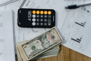 Máy tính, tiền mặt và giấy tờ trên bàn, minh họa tính chi phí nuôi mèo